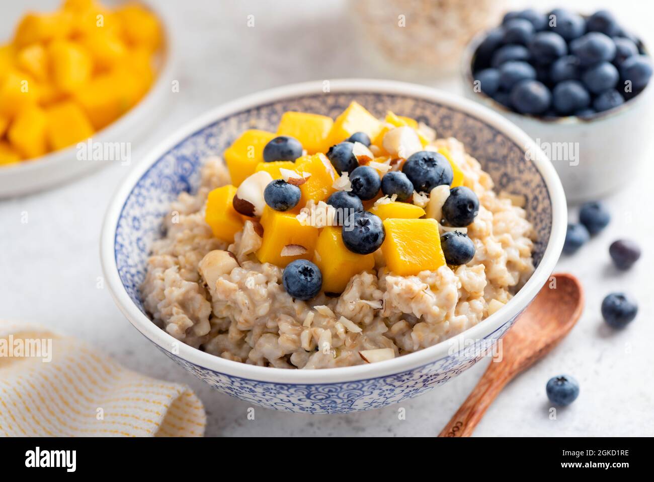 Oatmeal porridge with mango and blueberries in a bowl, closeup view. Weight loss, healthy diet breakfast food Stock Photo