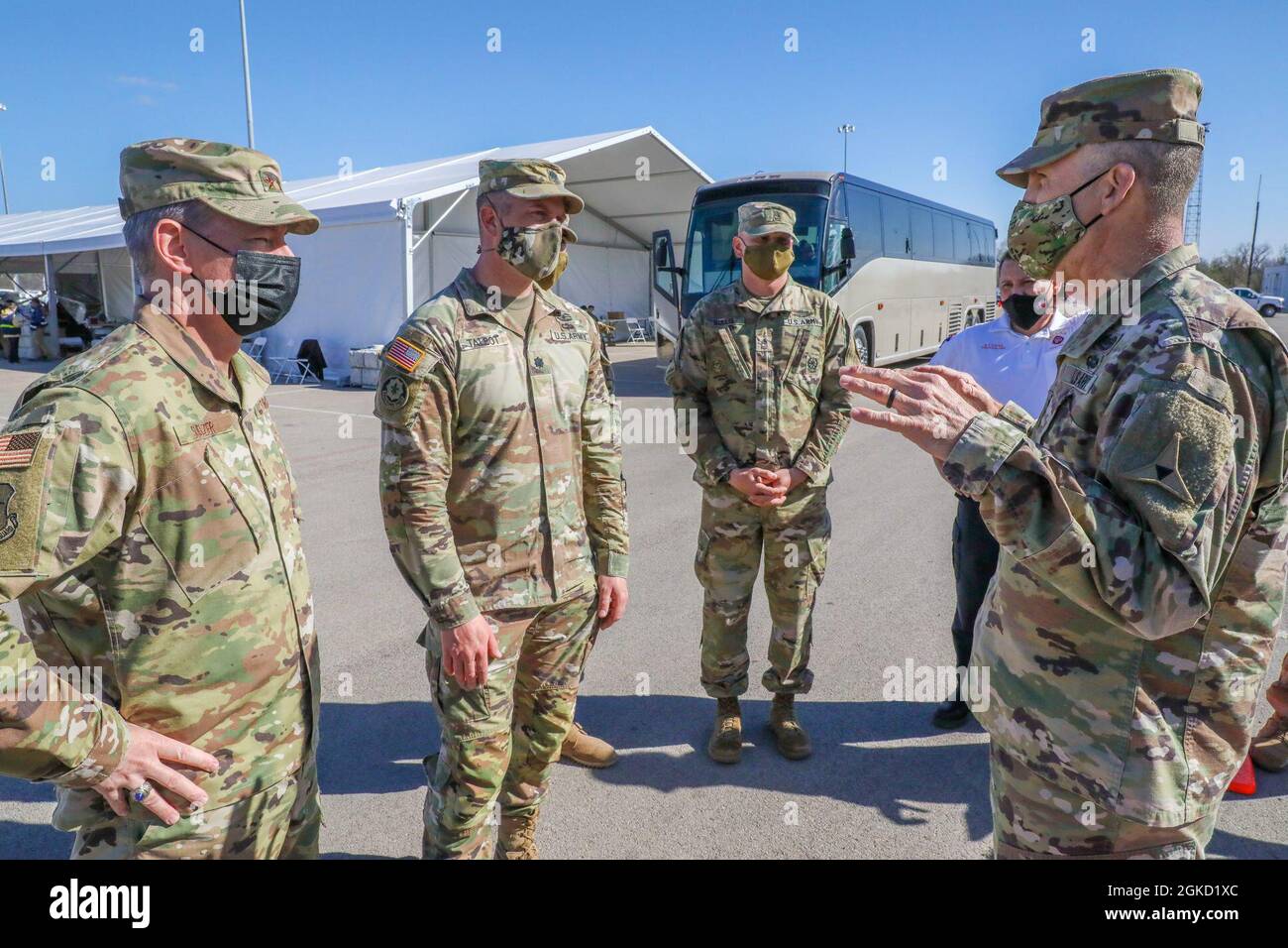 U.S. Air Force Maj. Gen. Thomas M. Suelzer, left, the Assistant Adjutant General-Air for the Texas National Guard, and U.S. Army Lt. Col. Nicholas Talbot, center left, commander of 1st Combined Arms Battalion, 63rd Armor Regiment, 2nd Armored Brigade Combat Team, 1st Infantry Division, speak to U.S. Army Lt. Gen. Robert “Pat” White, right, III Armored Corps and Fort Hood, Texas, commanding general, at the Fair Park Community Vaccination Center (CVC) in Dallas, March 17, 2021. The officers discussed CVC operations and the Department of Defenses’ role in assisting the Federal Emergency Managemen Stock Photo