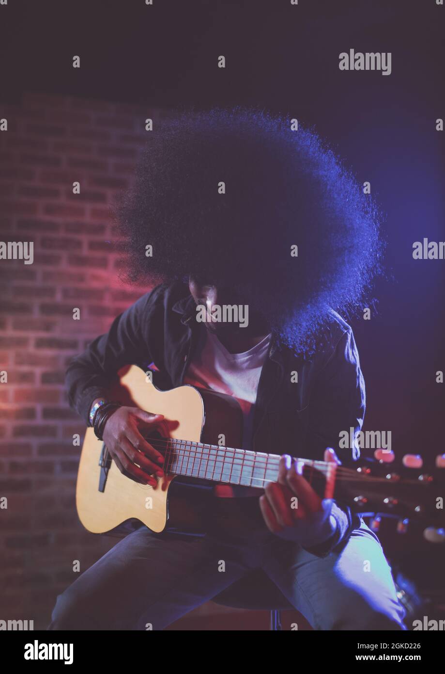 African american male musician playing guitar sitting on a table ...