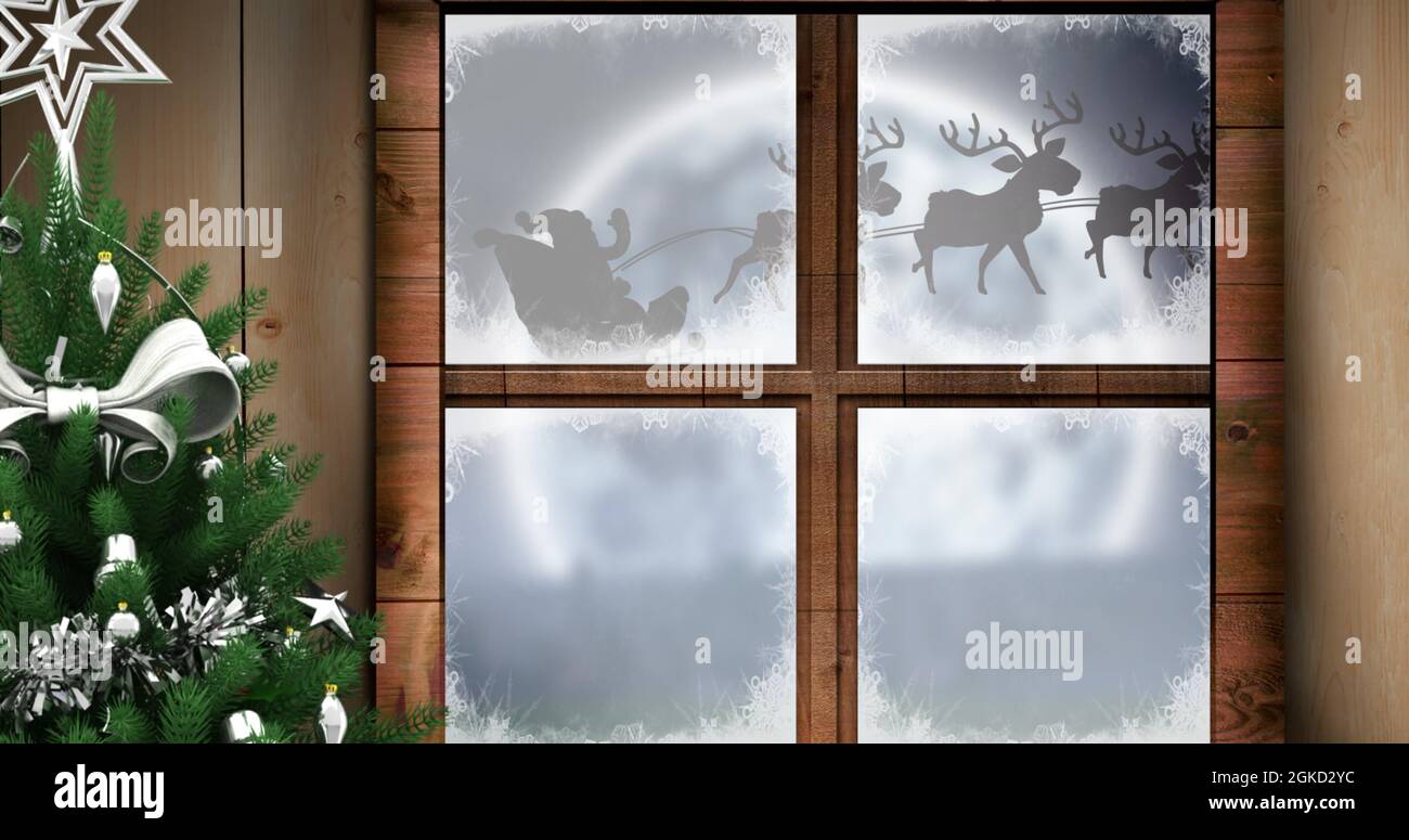 Digital image of christmas tree and wooden window frame against black silhouette of santa claus Stock Photo
