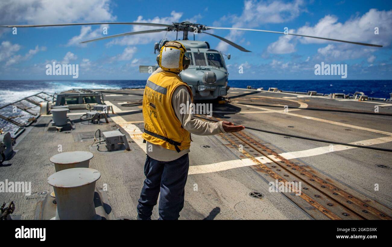 PACIFIC OCEAN (March 17, 2021) U.S. Navy Boatswain’s Mate Seaman Javough Watson, from Plainfield, N.J., signals to the pilots of an MH-60R Sea Hawk, assigned to the “Magicians” of Helicopter Maritime Strike Squadron (HSM) 35, on the flight deck of the Arleigh Burke-class guided-missile destroyer USS John Finn (DDG 113) March 17, 2021. John Finn, part of the Theodore Roosevelt Carrier Strike Group, is on a scheduled deployment to the U.S. 7th Fleet area of operations. As the U.S. Navy’s largest forward-deployed fleet, 7th Fleet routinely operates and interacts with 35 maritime nations while con Stock Photo