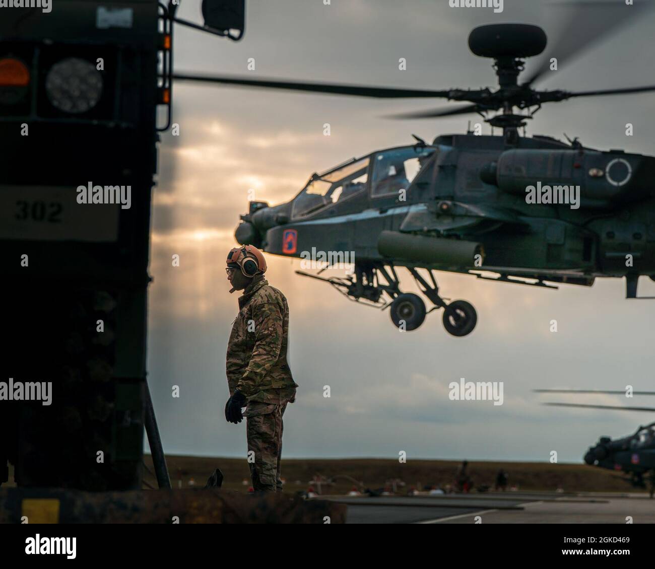 U.S. Army Spc. Brian Johnson, an ammunition specialist assigned to the 12th Combat Aviation Brigade, turns away from the rotor blast as a fully-fueled AH-64 launches from the forward area rearming and refueling point during Operation Eminent Strike on Mar. 17, 2021, at Katterbach Army Airfield. Stock Photo