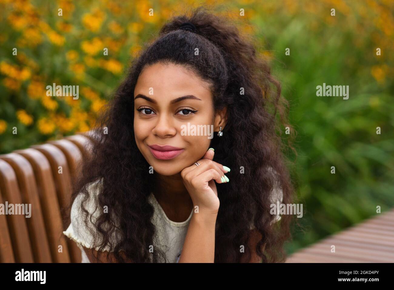 Dark skinned brunette Female with Loose Wavy Curls African American Hair. Outdoor Lifestyle Portrait of African American Young Woman. Hipster Mixed Race Black Girl. Multiracial Person. Soft focus. Stock Photo