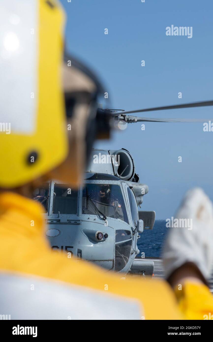 SAGAMI WAN (March 17, 2021) - Boatswain's Mate 2nd Class Hilary Huff, from Traverse City, Michigan, gives hand signals to pilots of an MH-60S Seahwak helicopter from the "Golden Falcons" of Helicopter Sea Combat Squadron (HSC) 12 prior to flight operations on the flight deck of U.S. 7th Fleet flagship USS Blue Ridge (LCC 19). Blue Ridge is the oldest operational ship in the Navy and, as 7th Fleet command ship, actively works to foster relationships with allies and partners in the Indo-Pacific Region. Stock Photo