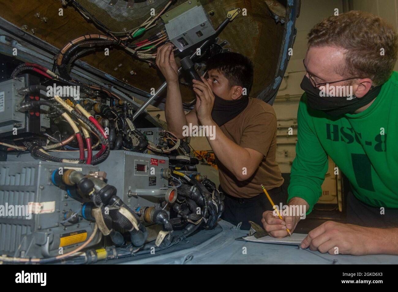 INDIAN OCEAN (March 18, 2021) – U.S. Navy Aviation Electrician’s Mate 1st Class Frederick Navarro, from Cotabato City, Philippines, left, and Aviation Machinist’s Mate 1st Class Bryan Myers, from Matthews, N.C., assigned to the “Eightballers” of Helicopter Sea Combat Squadron (HSC) 8, inspect fuses inside an MH-60S Sea Hawk in the hangar bay of the aircraft carrier USS Theodore Roosevelt (CVN 71) March 18, 2021. The Theodore Roosevelt Carrier Strike Group is on a scheduled deployment to the U.S. 7th Fleet area of operations. As the U.S. Navy’s largest forward-deployed fleet, 7th Fleet routinel Stock Photo