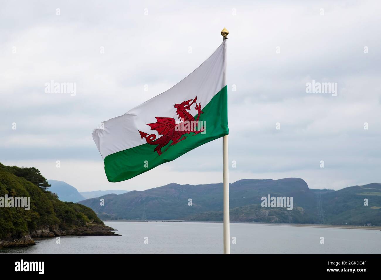 The Welsh National Flag, the Red Dragon (Y Ddraig Goch) flying  on the west coast of Wales with Snowdonian mountains in the background Stock Photo