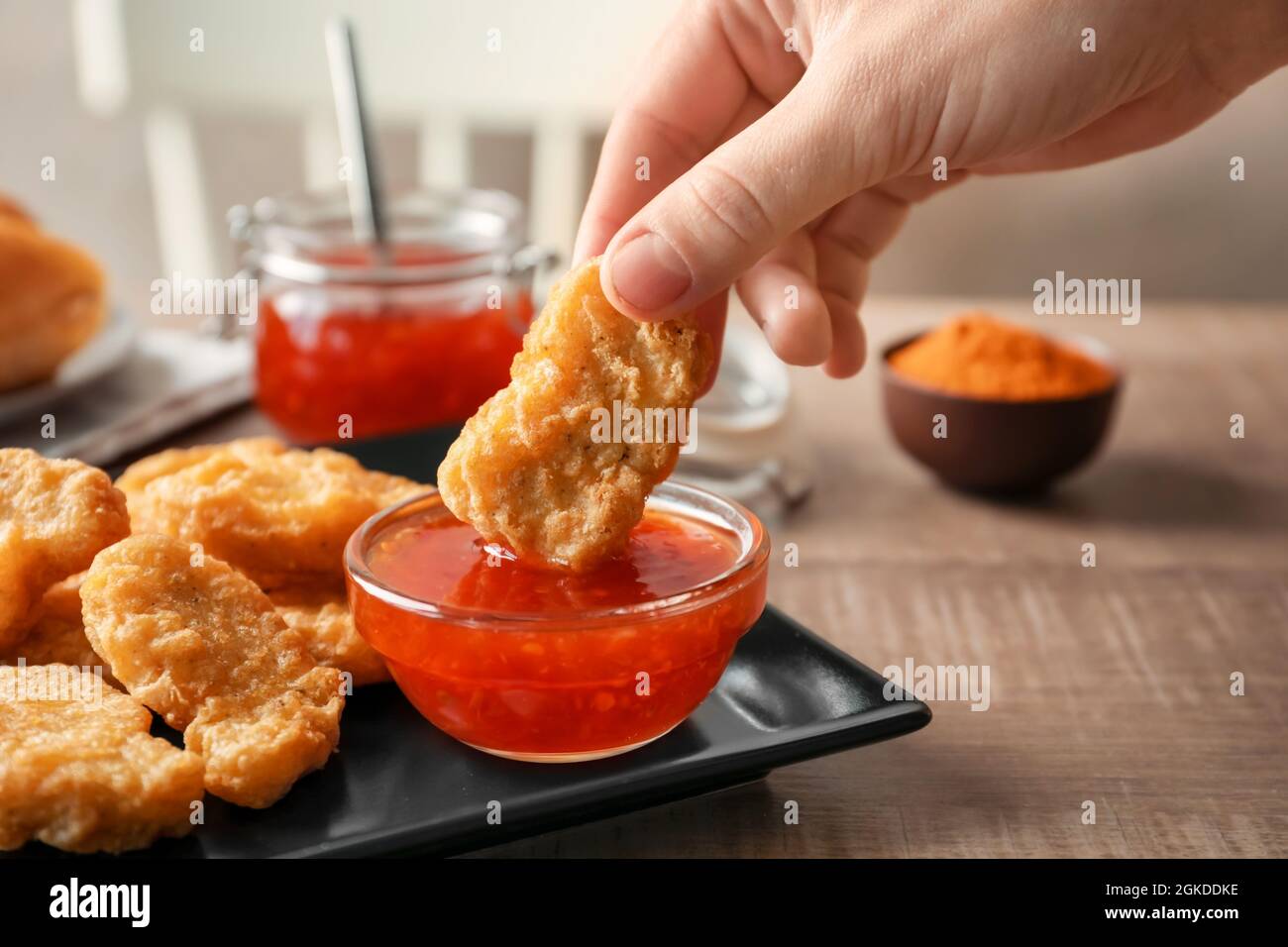 Person dipping chicken nugget in chili sauce indoors Stock Photo Alamy