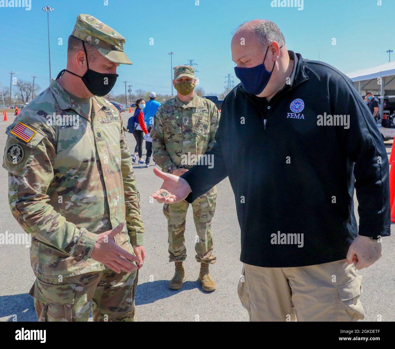 U.S. Army Lt. Col. Nicholas Talbot (left), commander of 1st Combined Arms Battalion, 63rd Armor Battalion, 2nd Armored Brigade Combat Team, 1st Infantry Division, receives a coin from Robert “Bob” Fulton (right), the Acting Administrator of the Federal Emergency Management Agency (FEMA) at the Fair Park Community Vaccination Center (CVC) in Dallas, March 20, 2021. 1st Infantry Division Soldiers deployed to Dallas in February 2021 to assist FEMA in its vaccination efforts and have helped the CVC reach a site record of administering over 9,000 vaccines to local community members in one day. U.S. Stock Photo