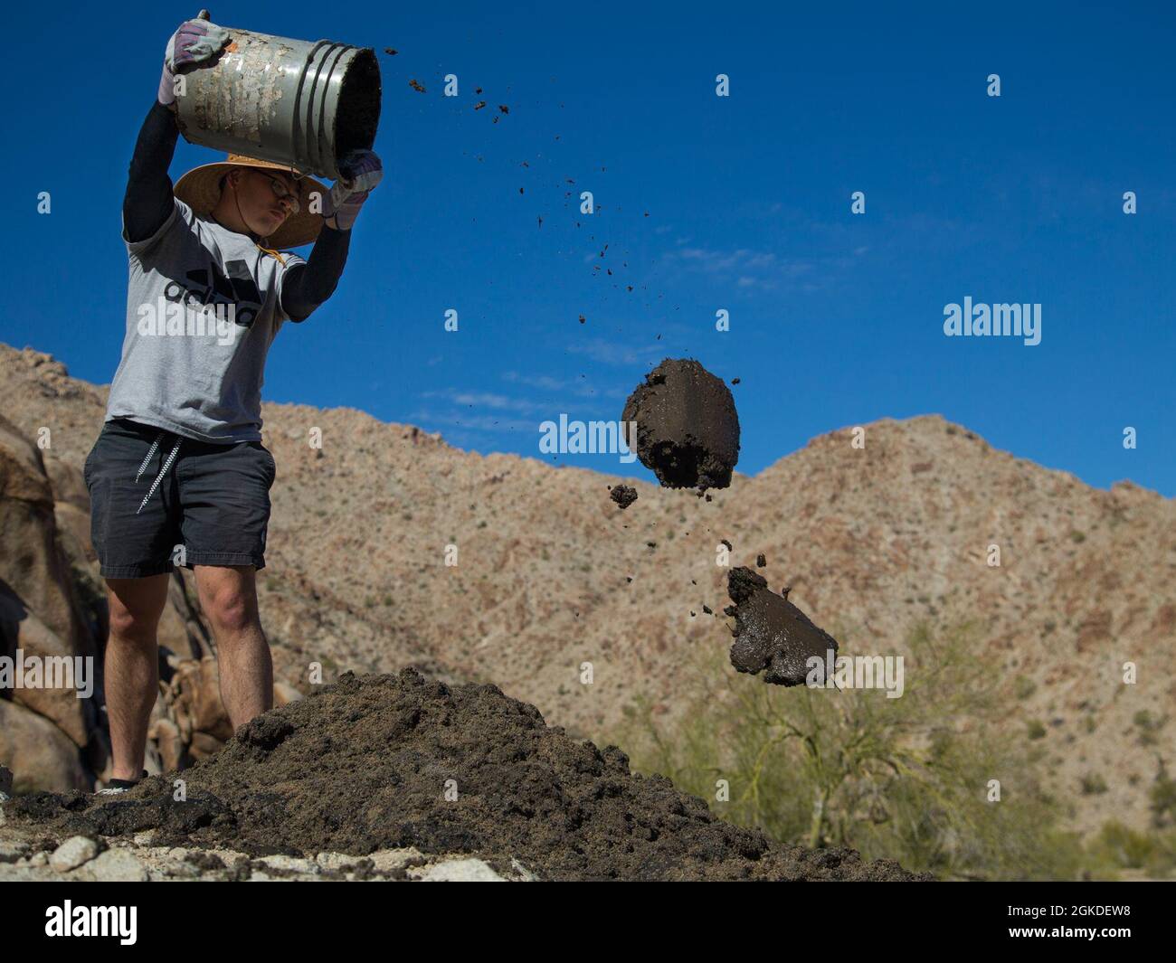 A U.S. Marine volunteer with the Single Marine Program (SMP) throws built-up silt from a Bighorn Sheep watering hole at the Betty Lee Tank in Yuma, Ariz., Mar 20, 2021. The SMP sends volunteers to help with community efforts and build relations between the community and the Marine Corps. Stock Photo