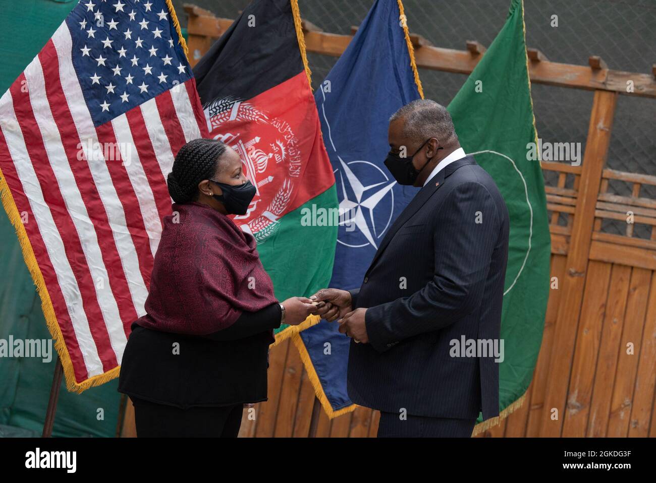 Secretary of Defense Lloyd J. Austin III presents his coin in recognition of outstanding work