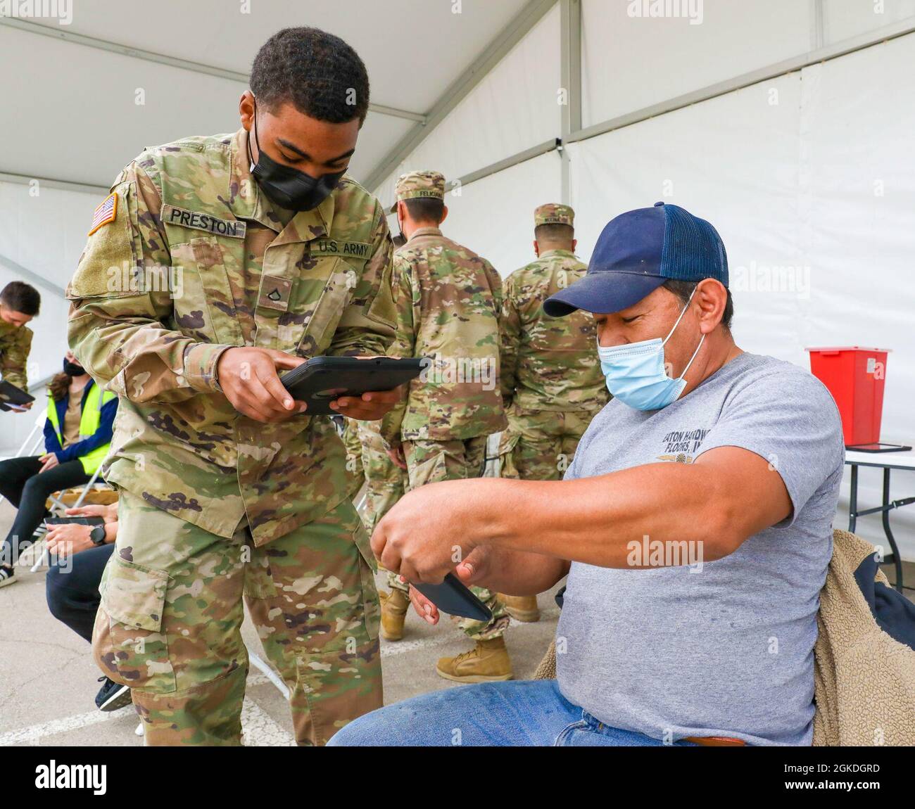 U.S. Army Pfc. Kyle Preston, a M1 armor vehicle crew member with 1st Combined Arms Battalion 63rd Armor Regiment, 2nd Armored Brigade Combat Team, 1st Infantry Division, speaks with Juan Castillo, a Dallas County community member, at the Fair Park Community Vaccination Center (CVC) in Dallas, March 22, 2021, about Castillo receiving a COVID-19 vaccination shot. On this day, the Dallas CVC reached a total of over 200,000 COVID-19 vaccinations administered to local Dallas community members since its opening in January 2021. U.S. Northern Command, through U.S. Army North, remains committed to pro Stock Photo
