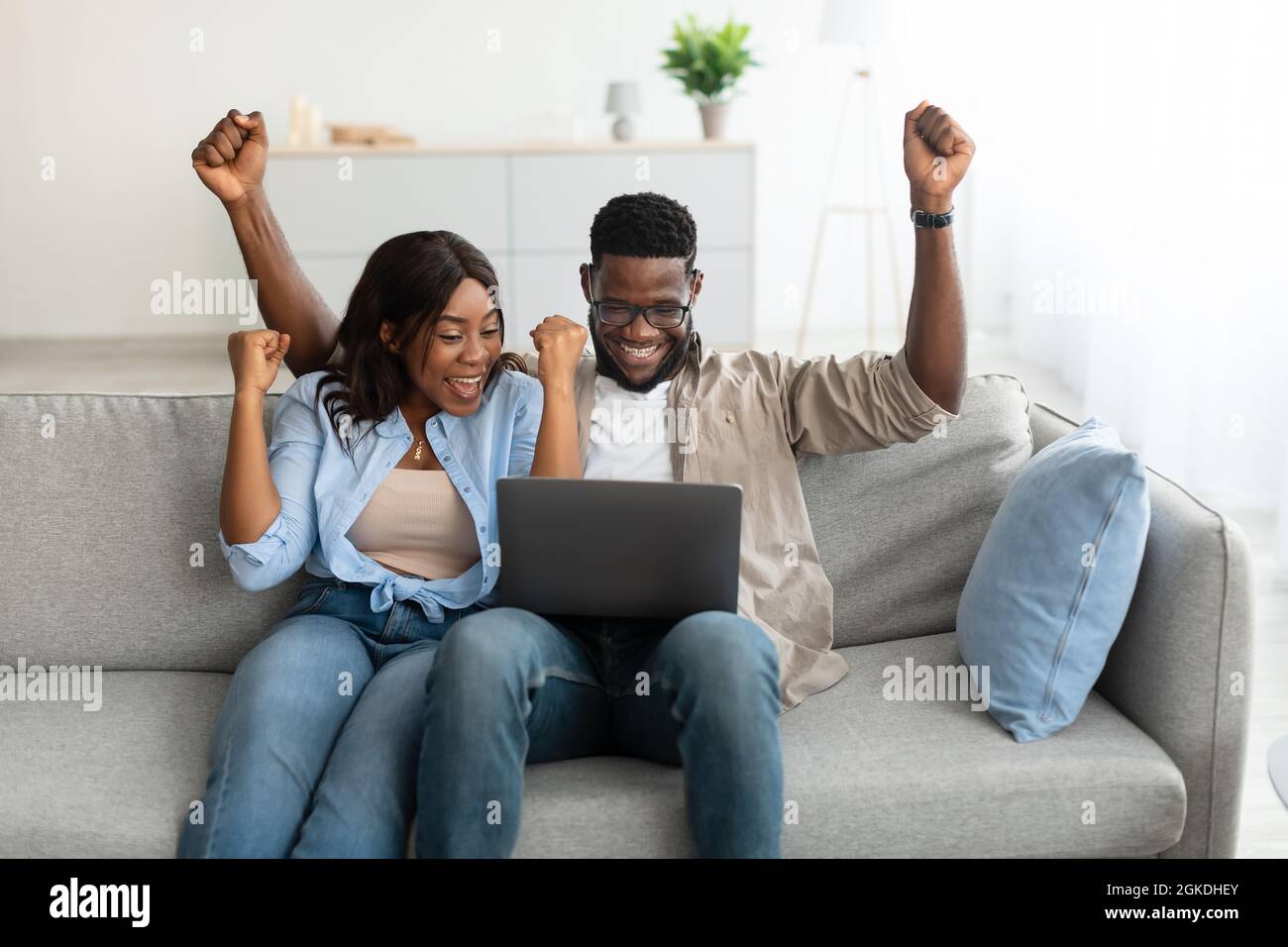 African american couple using laptop, celebrating win Stock Photo - Alamy