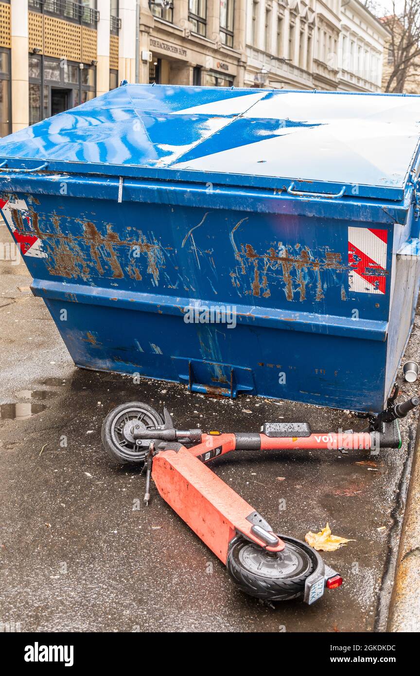 An overturned electric escooter or e-scooter from the company VOI in front of a scrap container in Berlin Stock Photo