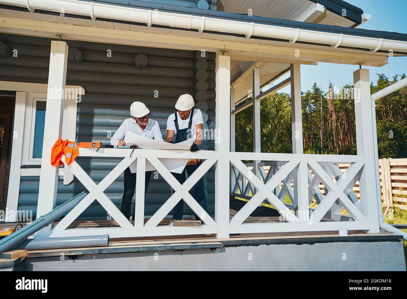 Two male workers on porch inspecting technical document Stock Photo
