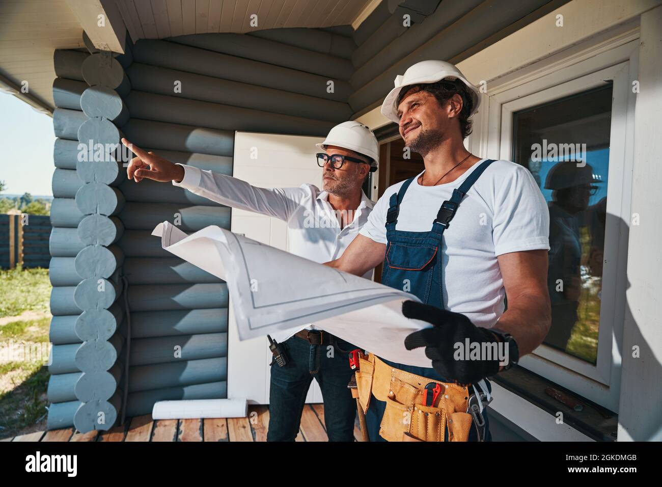 Housebuilder demonstrating something outside to pleased worker Stock Photo