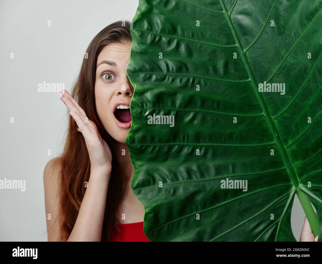 emotional woman covers half of her face with green leaf red swimsuit ...