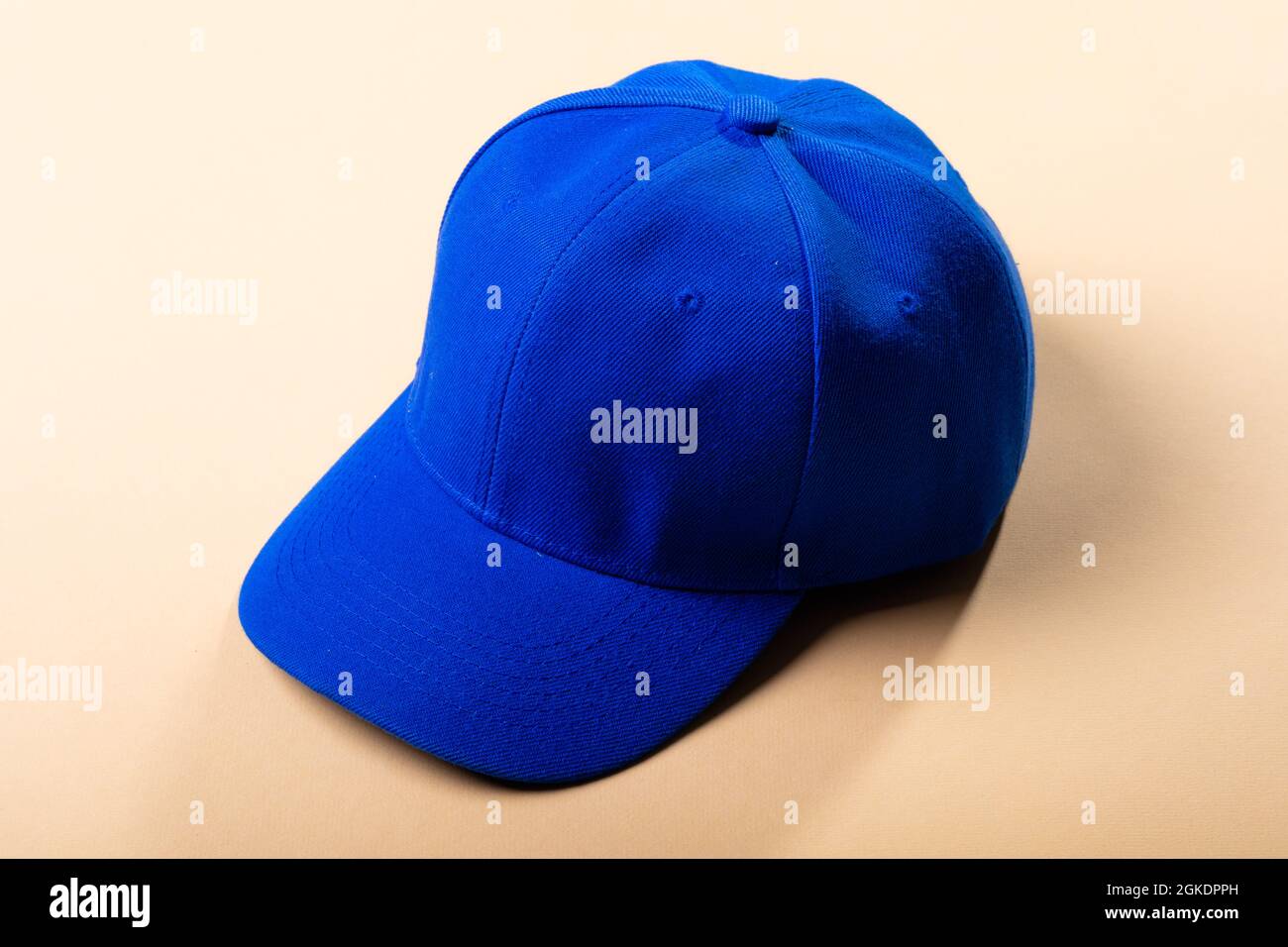 Composition of traditional peaked blue baseball cap on pale brown background Stock Photo