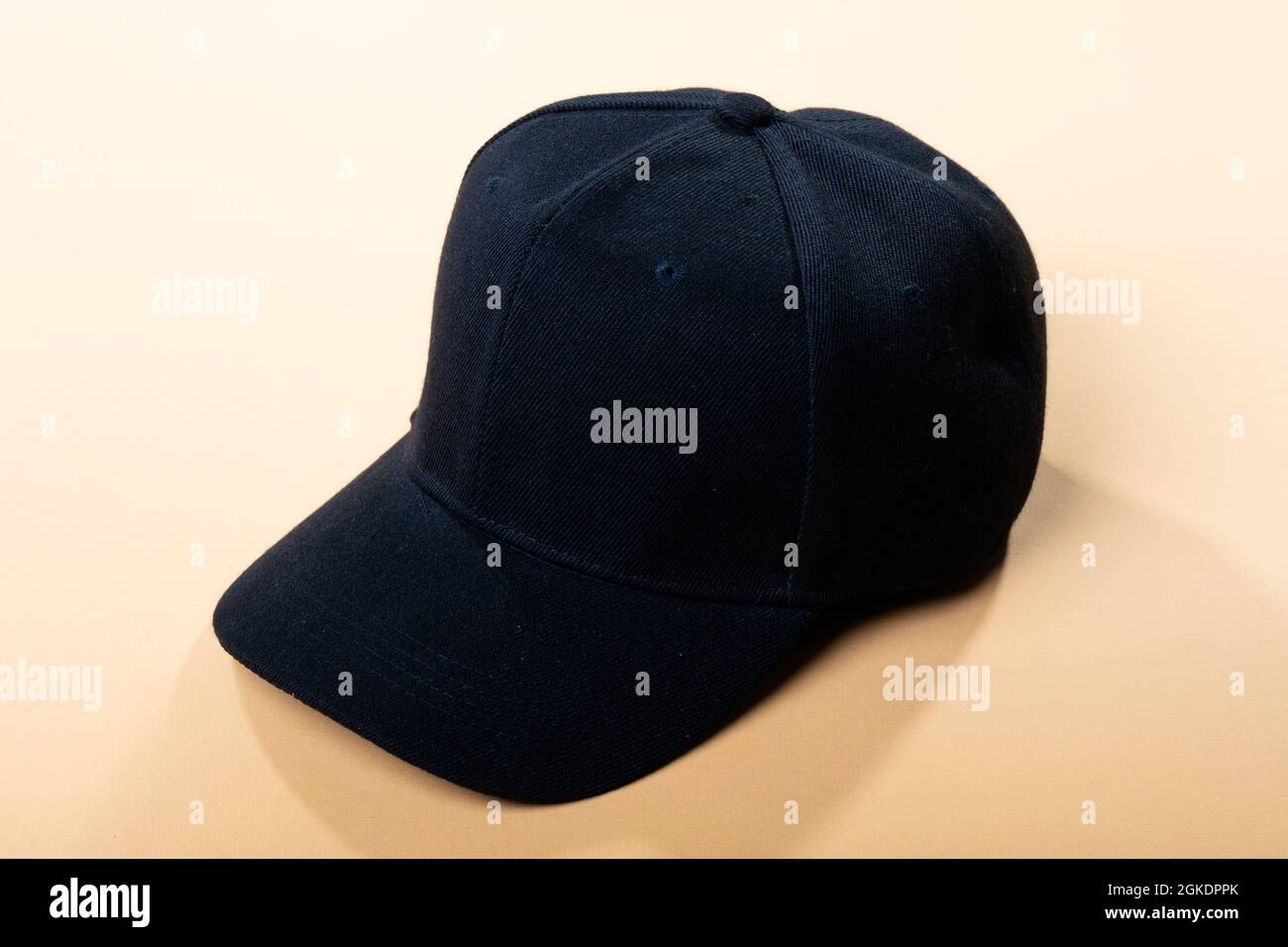 Composition of traditional peaked black baseball cap on pale brown background Stock Photo