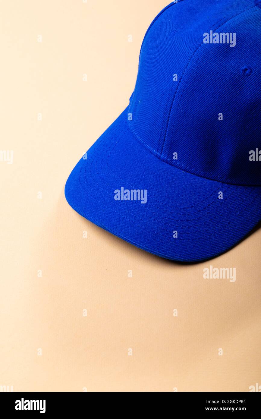 Composition of traditional peaked blue baseball cap on pale brown background Stock Photo