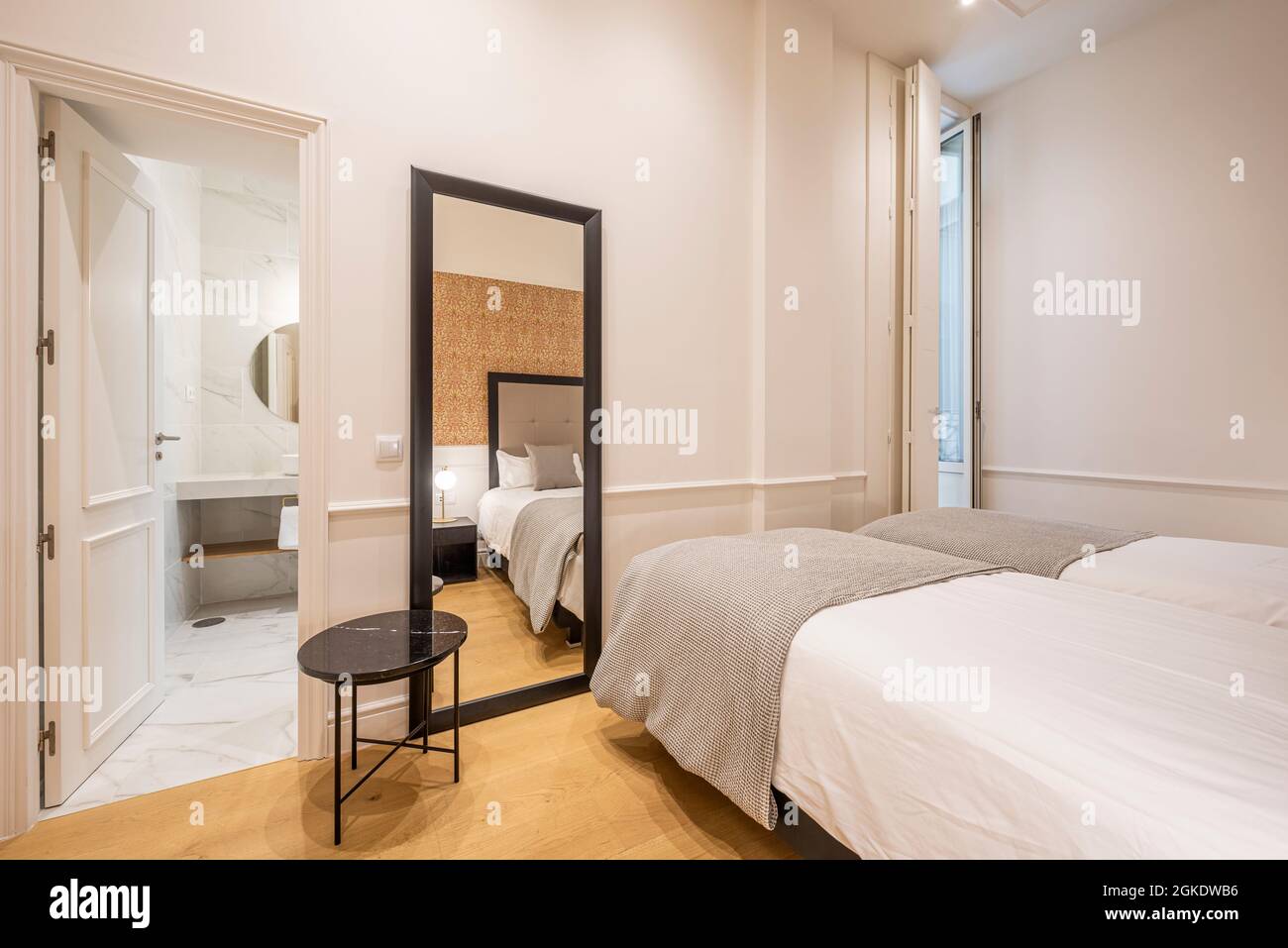 Bedroom with two beds and bathroom en suite, large full-length mirror in vacation rental apartment Stock Photo