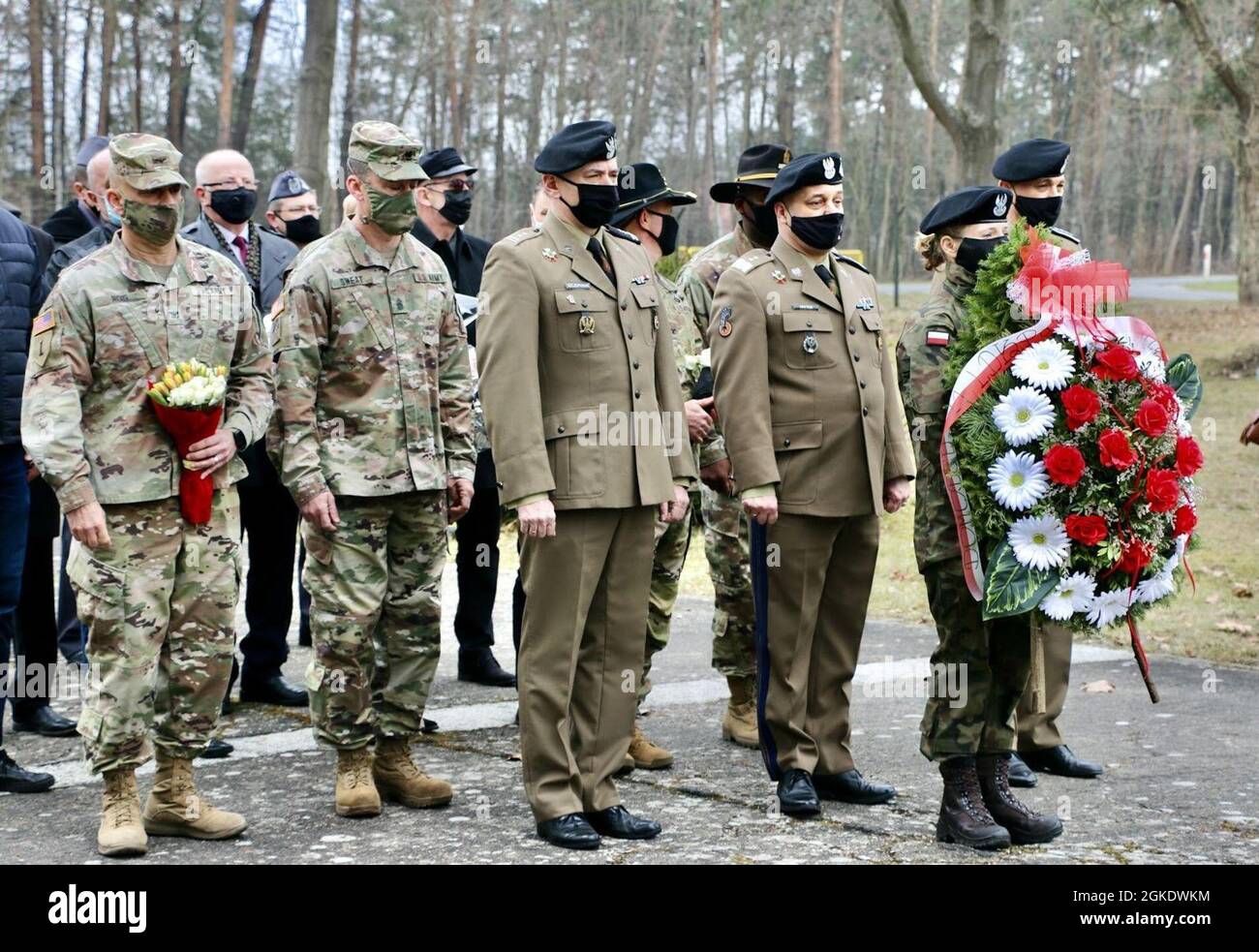 Army Col. Ricardo Roig (far left, holding flowers), 50th Regional Support Group (RSG) commander, and Command Sgt. Maj. Robert Sweat (second from the left in camouflage uniform), 50th RSG command sergeant major, attend a remembrance ceremony in Zagan, Poland, on Mar. 24, 2021, with representatives of the Polish and American militaries, as well as local officials. The ceremony commemorates the efforts of Allied service members who participated in the “Great Escape” from Stalag Luft III, a German prison-of-war camp, in March 1942. The 50th RSG, a Florida Guard unit based in Homestead, Florida, is Stock Photo