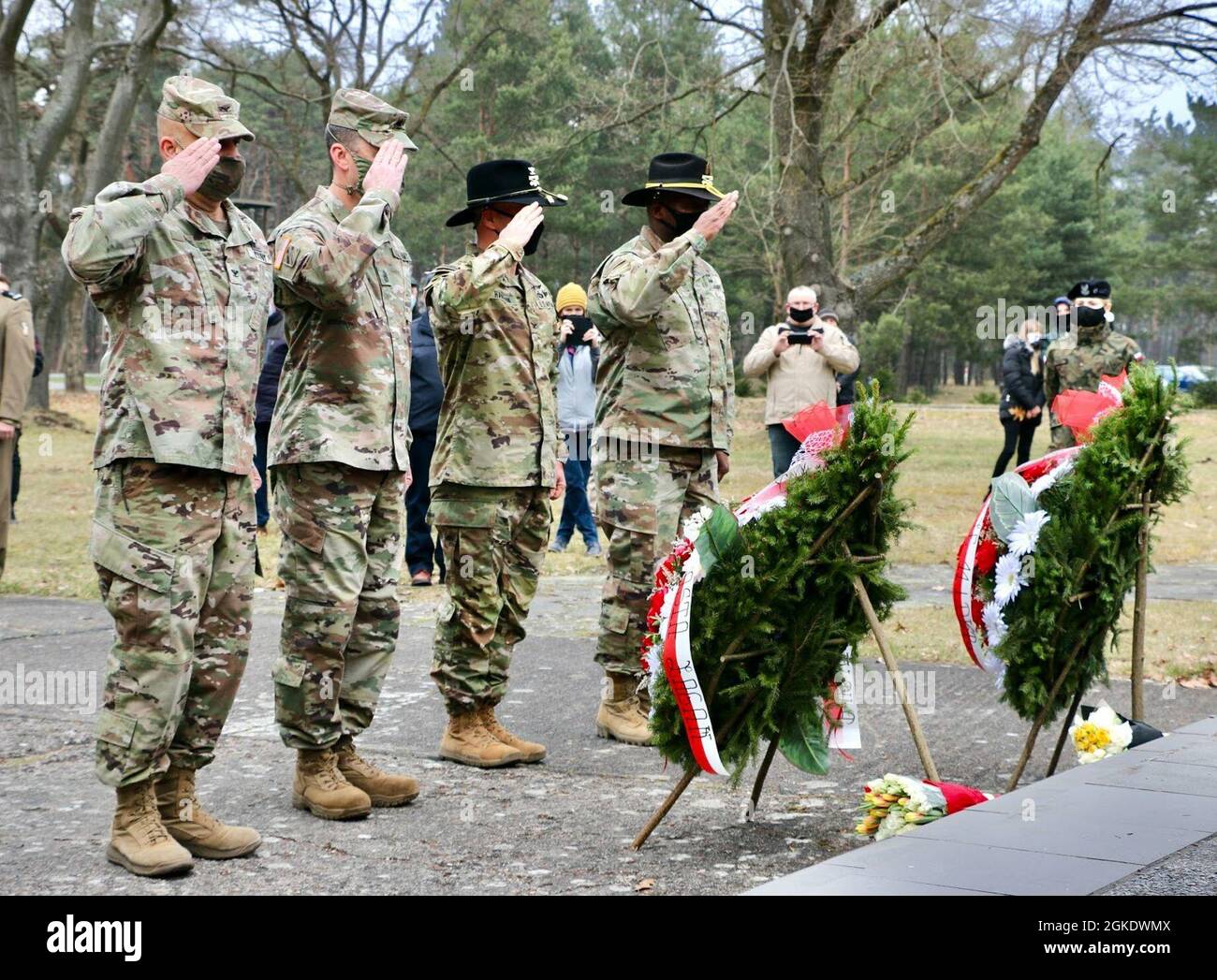 Command teams from two U.S. Army units salute at a remembrance ceremony in Zagan, Poland, on Mar. 24, 2021. Left to right (in camouflage uniforms): Army Col. Ricardo Roig, 50th Regional Support Group (RSG) commander, Command Sgt. Maj. Robert Sweat, 50th RSG command sergeant major, Army Col. Ryan Hanson, 1st Armored Brigade, 1st Cavalry Division (1ABCT 1CD) commander, and Command Sgt. Maj. Calvin Hall, 1ABCT 1CD command sergeant major. The ceremony commemorates the efforts of Allied service members who participated in the “Great Escape” from Stalag Luft III, a German prison-of-war camp, in Marc Stock Photo