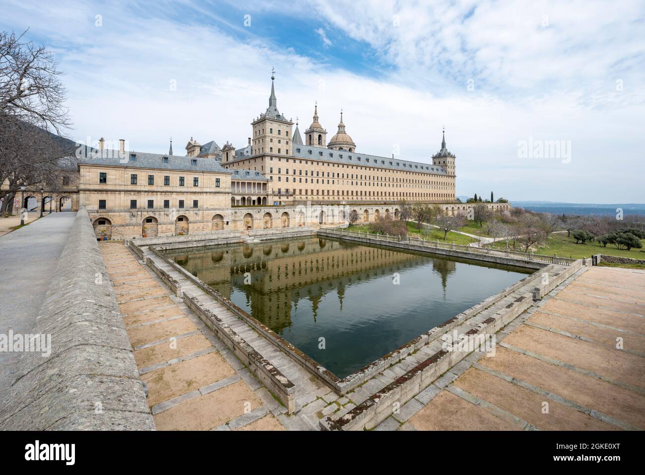 Panoramic of the Monastery of El Escorial with reflection in a rectangular pond and with the Sierra de Madrid in the background Stock Photo