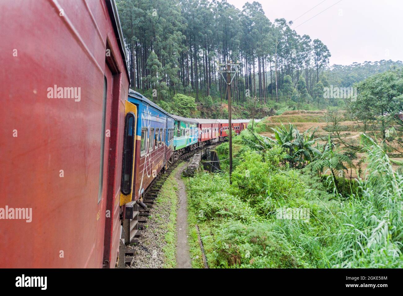 NANU OYA, SRI LANKA - JULY 16, 2016: Local train rides through a rural landscape near Nanu Oya village, Sri Lanka Stock Photo