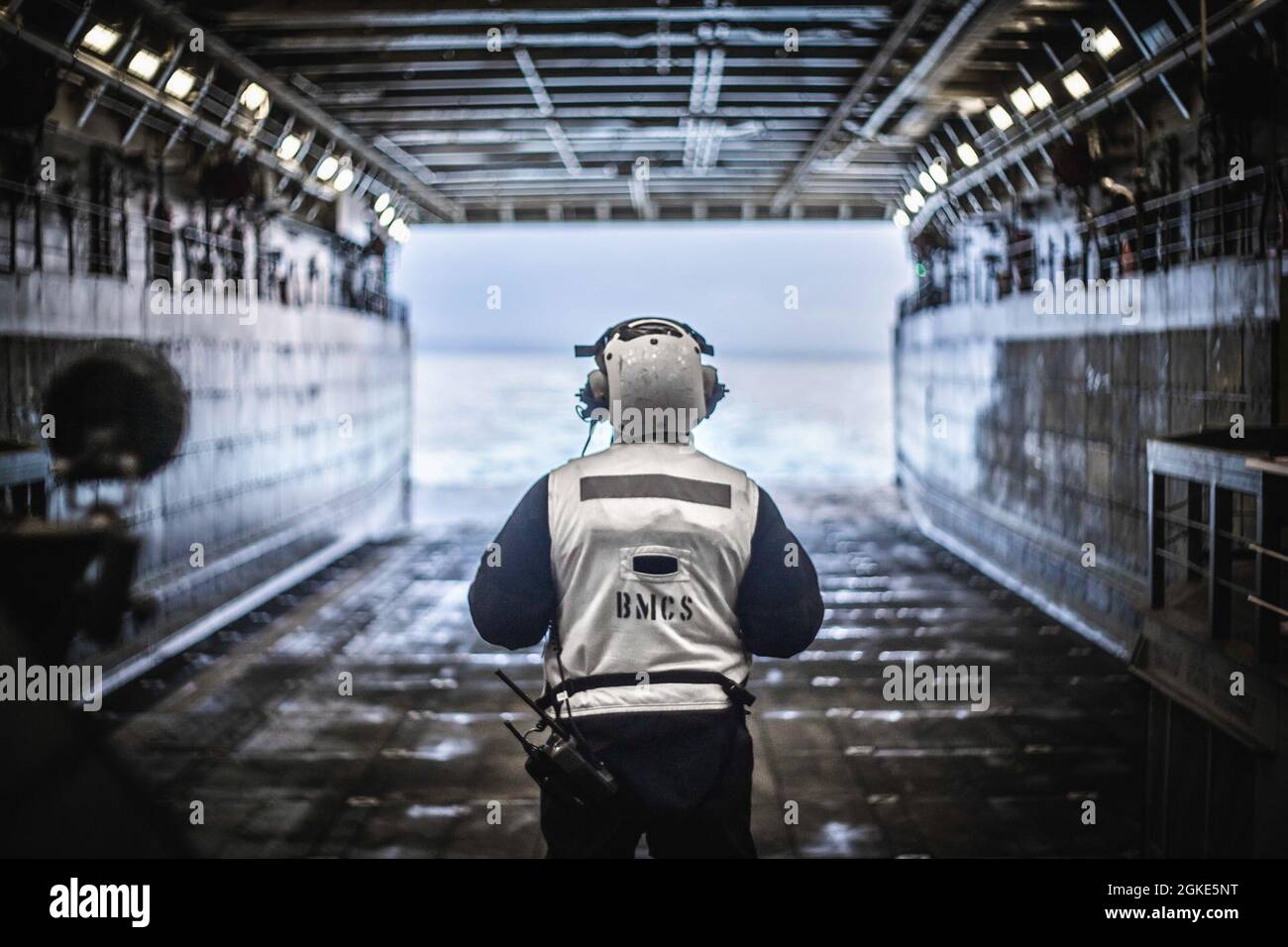 PACIFIC OCEAN (March 26, 2021) U.S. Navy Senior Chief Boatswain’s Mate Herns Brilliant, the deck department leading chief petty officer aboard San Antonio-class amphibious transport dock USS Portland (LPD 27), observes an empty well deck during a tactical surface offload. U.S. Navy and Marine Corps integration training provides the Essex Amphibious Ready Group/11th Marine Expeditionary Unit its first opportunity to plan, brief, and execute multiple mission packages. The Essex ARG is underway conducting routine operations in U.S. Third Fleet. Stock Photo
