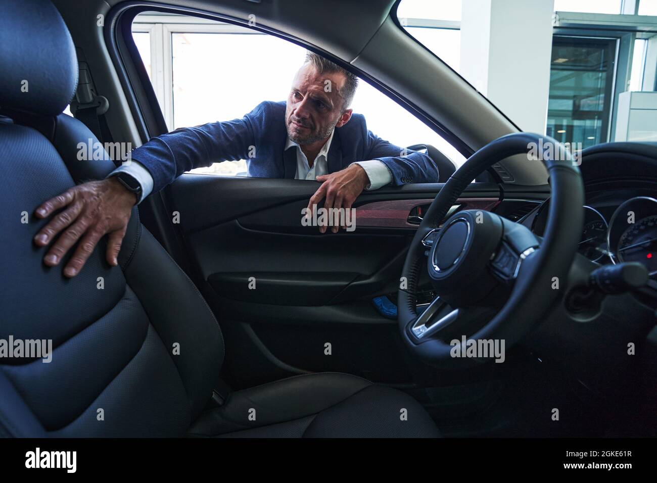 Modern car in showroom and salesman watching it Stock Photo
