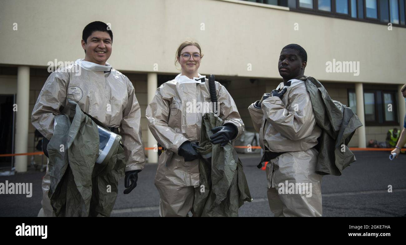 Three U.S. Air Force Airmen from the 52nd Medical Group Airmen pose for a photo near a decontamination site pop-up behind the Medical Group building at Spangdahlem Air Base, Germany, March 26, 2021. After the initial disaster simulation at the base theater, patients were transported to the decontamination site where Medical Group Airmen awaited their arrival and performed simulated decontamination procedures. Stock Photo