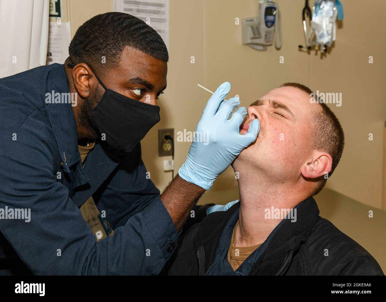 ADRIATIC SEA (Mar. 28, 2021) Hospital Corpsman 2nd Class Benjamin Richardson, left, collects a nasal swab sample from LT Jake Holland for COVID-19 testing aboard the Expeditionary Sea Base USS Hershel “Woody” Williams (ESB 4) in the Adriatic Sea, Mar. 28, 2021. Hershel “Woody” Williams is operating in U.S. Sixth Fleet to conduct interoperability training and build strategic partnerships with their African partners. Stock Photo