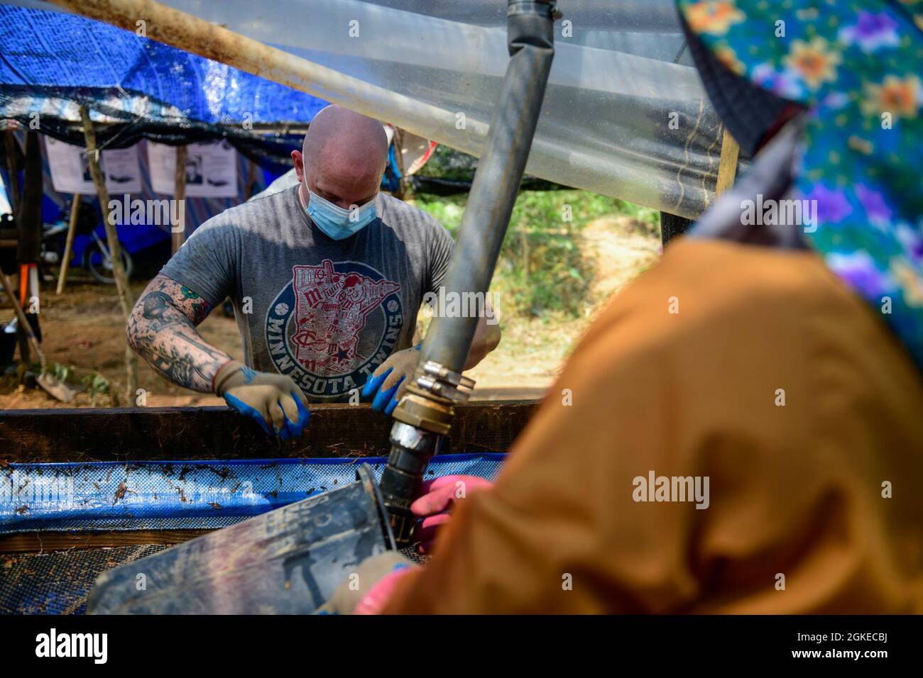 U.S. Air Force Staff Sgt. Marc Schoenherr, a Defense POW/MIA Accounting Agency (DPAA) recovery team noncommissioned officer augmentee, and a local Vietnamese worker sift through dirt on the wet-screen during excavation operations in Ha Tinh Province, Socialist Republic of Vietnam, March 29, 2021. DPAA’s mission is to achieve the fullest possible accounting for missing and unaccounted-for U.S. personnel to their families and our nation. Stock Photo