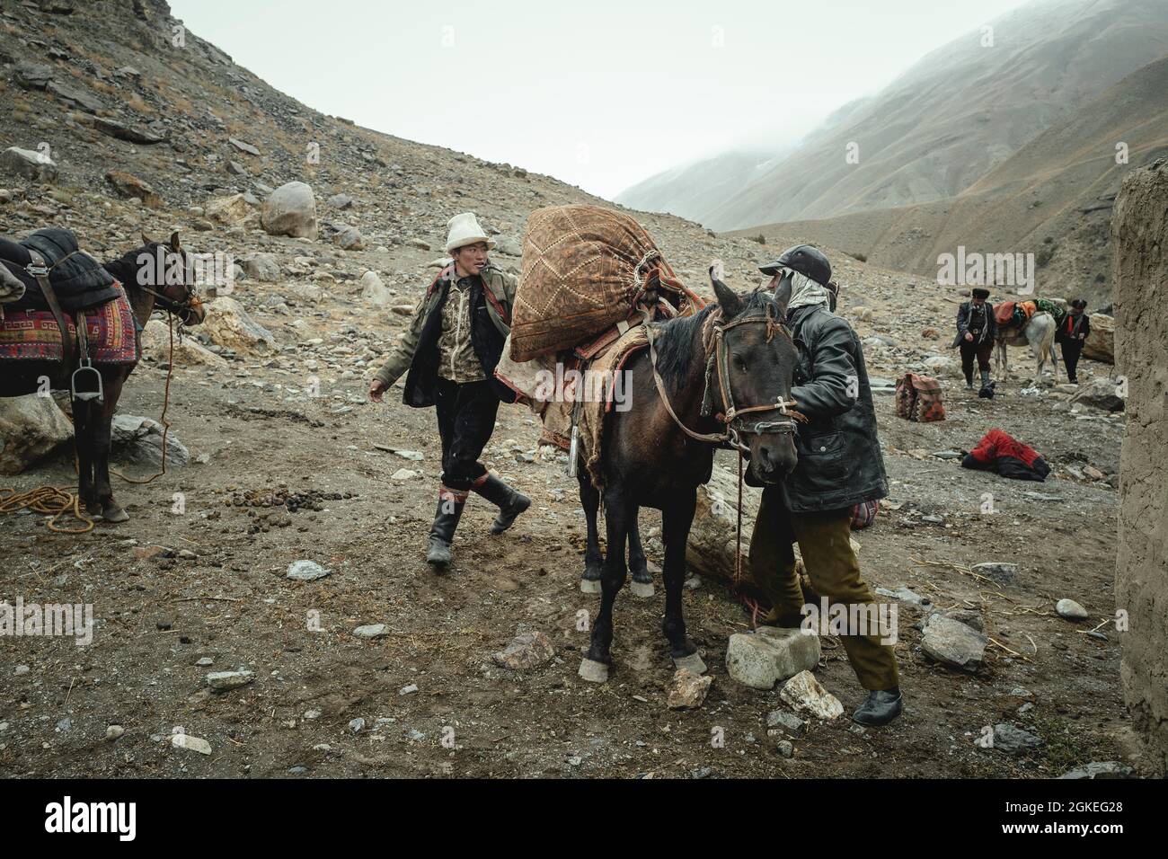 Two men loading a packhorse, Kyrgyz nomads, Wakhan Corridor, Badakhshan, Afghanistan Stock Photo