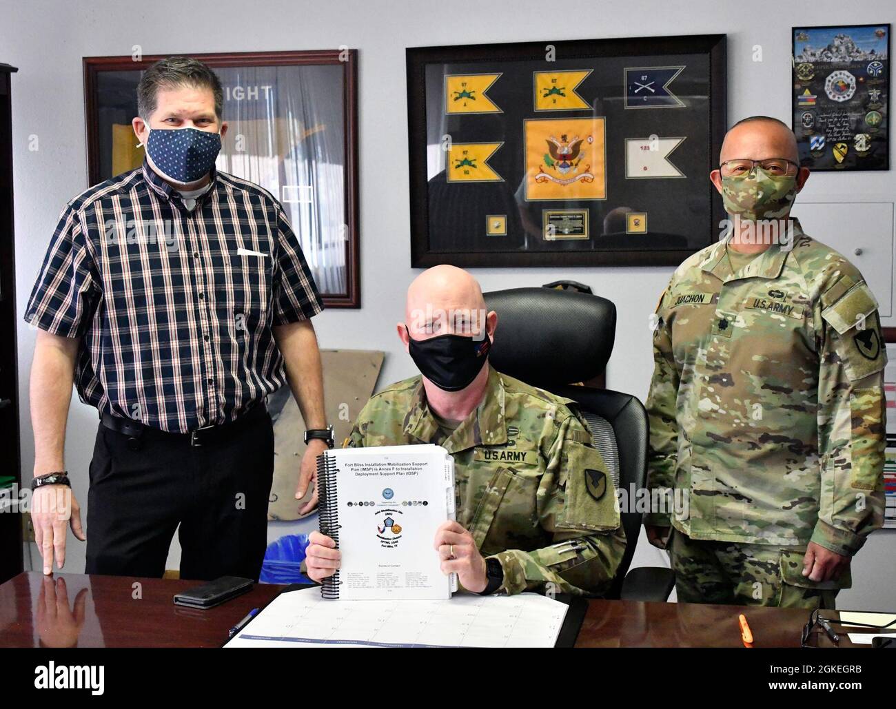 U.S. Army Col. Stu James, commander, U.S. Army Garrison Fort Bliss, center, is accompanied by Mr. Jaymes Picott, mobilization chief, left, and Lt. Col. John Juachon, mobilization planner, right, both assigned to the Mobilization Division, Directorate of Plans, Training, Mobilization & Security (DPTMS), after signing the Fort Bliss Installation Mobilization Support Plan, March 31, 2021, Fort Bliss, Texas. Stock Photo