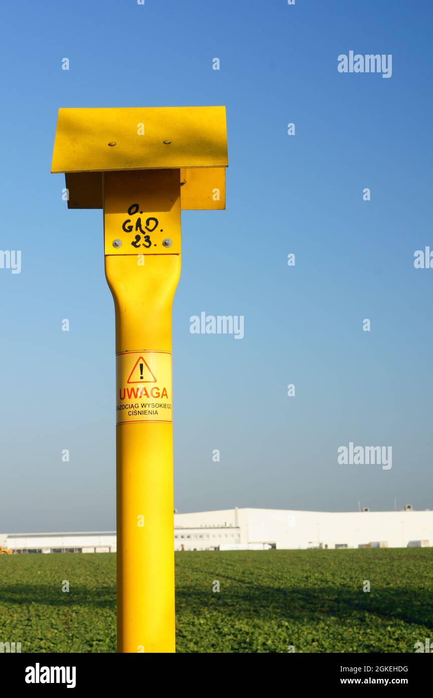 Yellow pole with a warning sign for natural gas pipeline Stock Photo