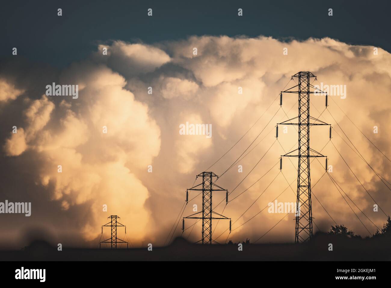 Transmission towers under the sky with big fluffy clouds Stock Photo ...