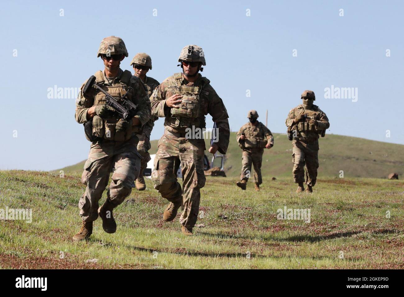 U.S. Army Spc. Alex Hammack of the California National Guard’s Delta Company, 1st Battalion, 184th Infantry Regiment, 79th Infantry Brigade Combat Team, carries an M320 grenade launcher and runs to a firing position along with range cadre, safety and scorers April 1, 2021 during Cal Guard's 2021 Best Warrior Competition at Camp San Luis Obispo. Stock Photo