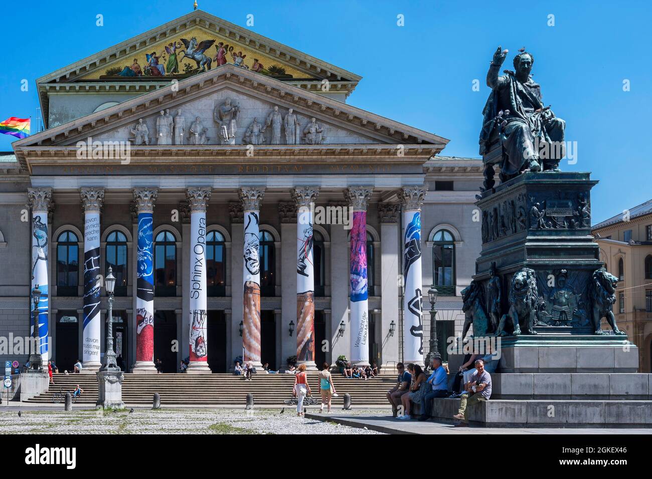 Opera, National Theatre with colorfully clad columns, rainbow flag and monument of King Maximilian II. Joseph at Max-Joseph-Platz, Munich, Upper Stock Photo