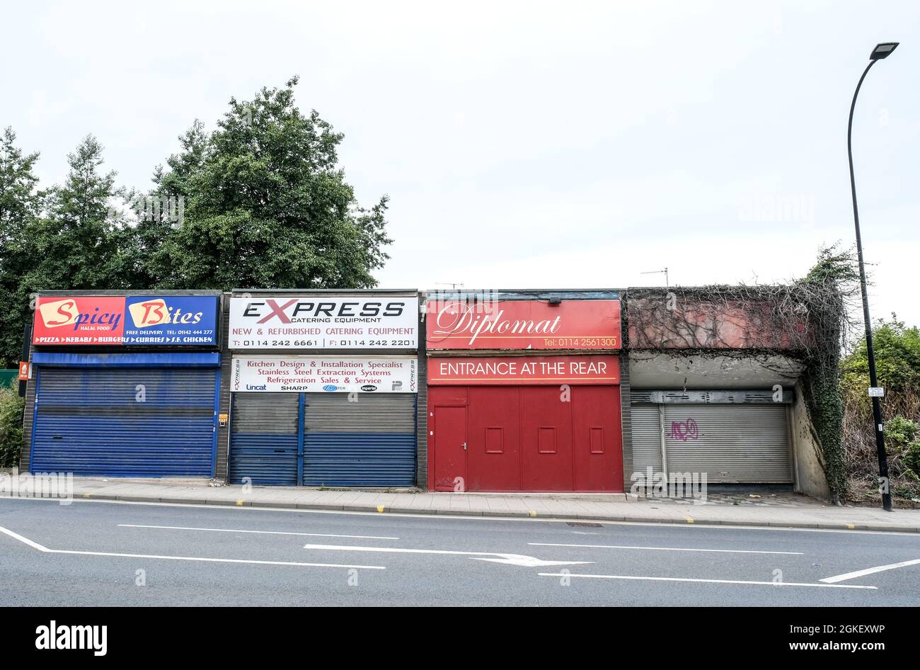 A row of semi derelict and decaying shop fronts in an industrial corner of inner city Sheffield. Stock Photo