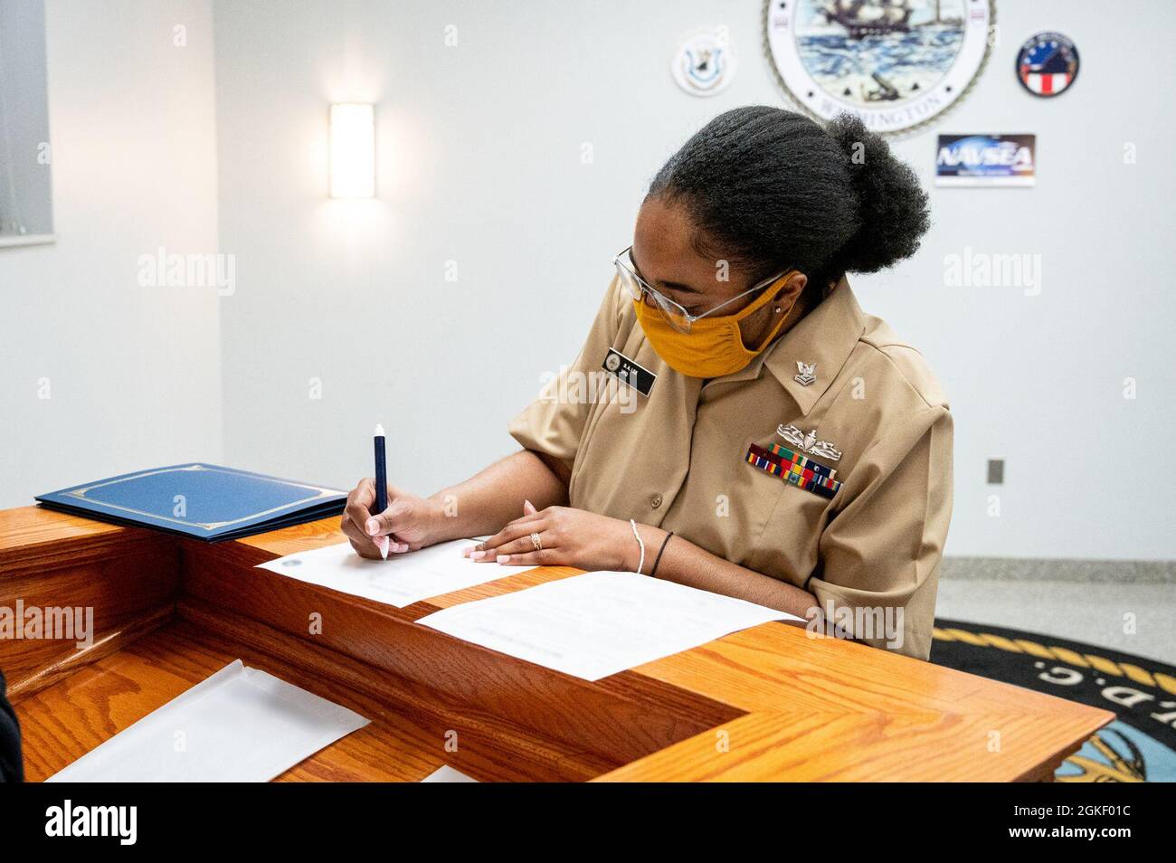 WASHINGTON, DC (April 2, 2021) – Culinary Specialist 2nd Class Sheniqua Lee signs reenlistment paperwork following a ceremony onboard Washington Navy Yard. Stock Photo