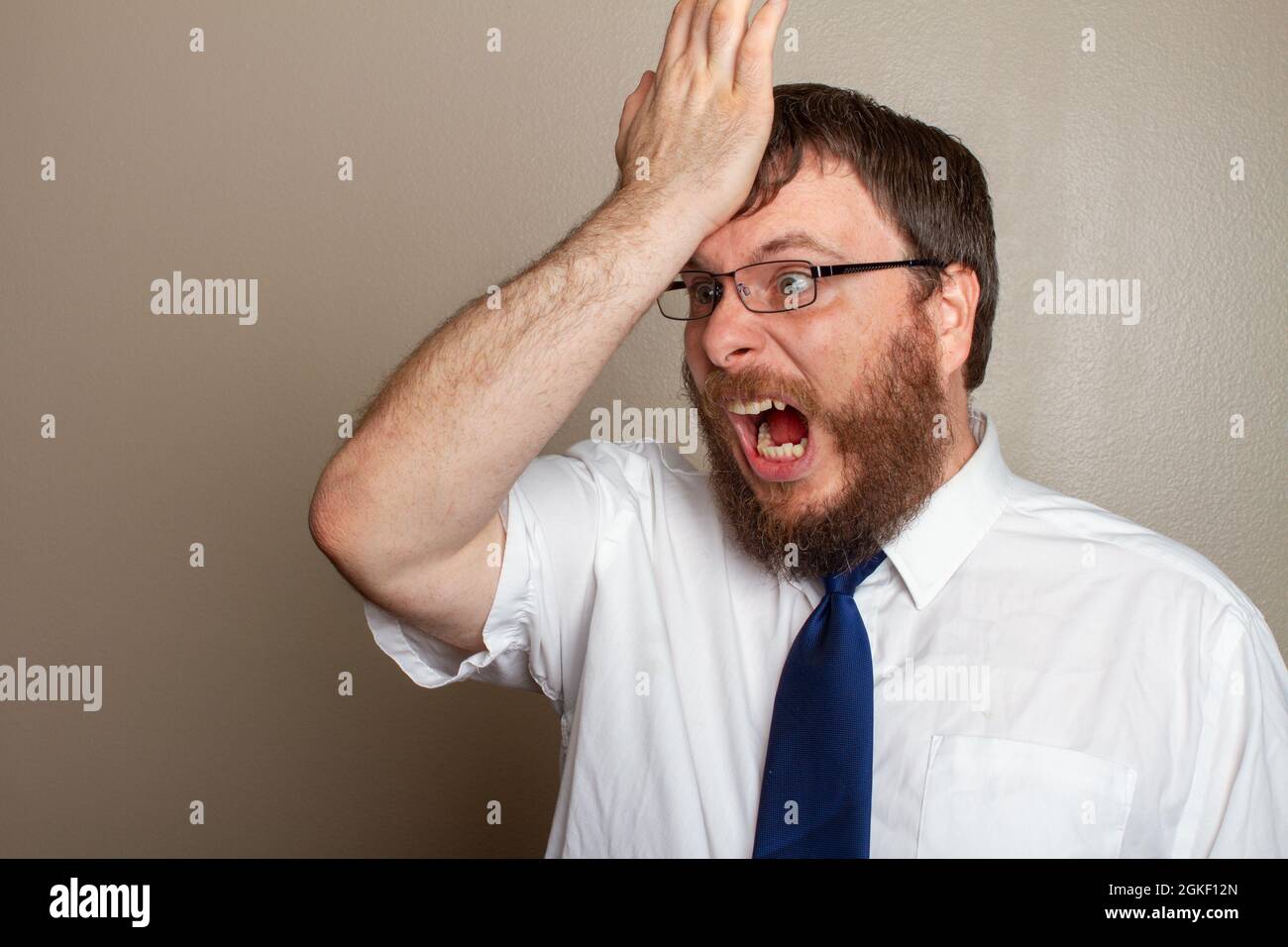 man screaming in anger while banging his forhead Stock Photo