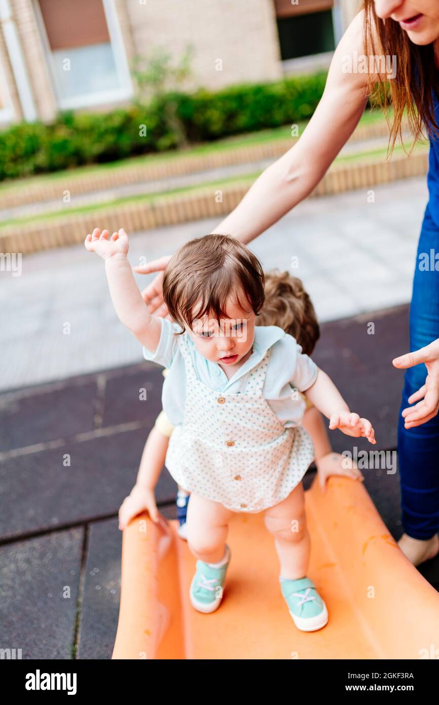 three-year-old baby balancing on a slide in a park. falling risk Stock ...