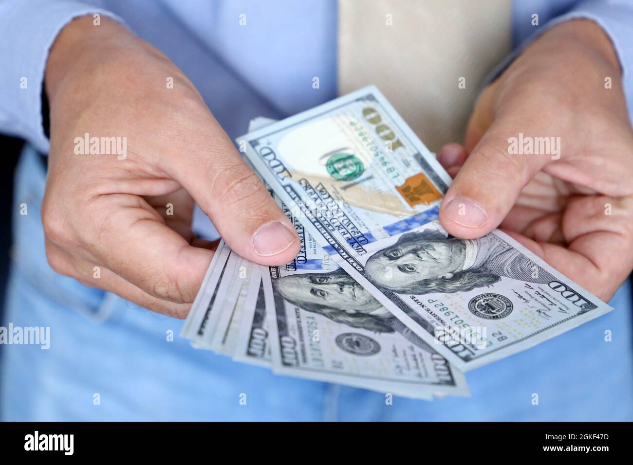 US dollars in male hand close up, man in business clothes counting the money. Concept of bribe, salary, financial assistance or loan Stock Photo