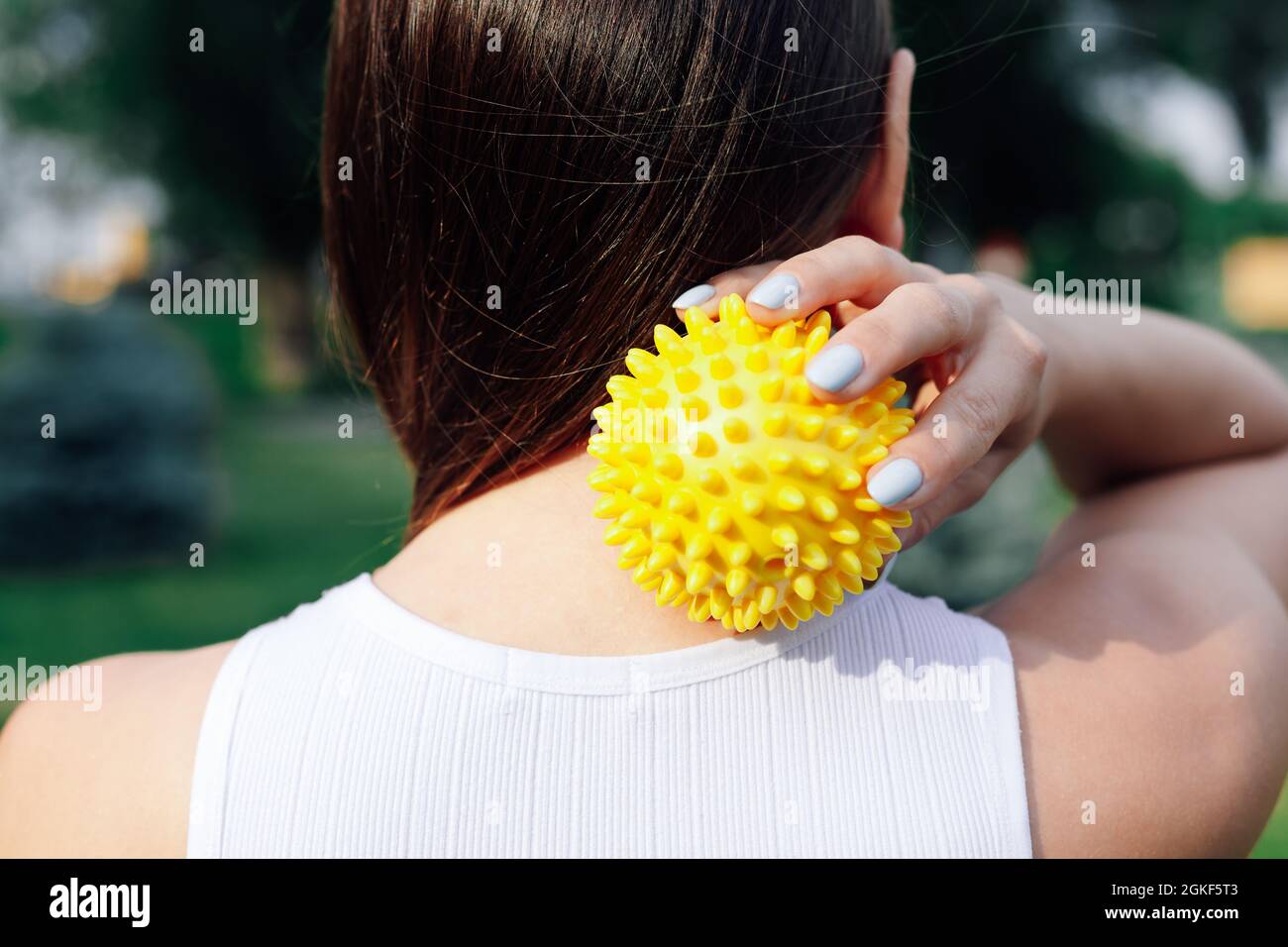 Close Up On Back Of Young Woman Doing Neck And Shoulder Massage With Spiky Rubber Ball Relaxing