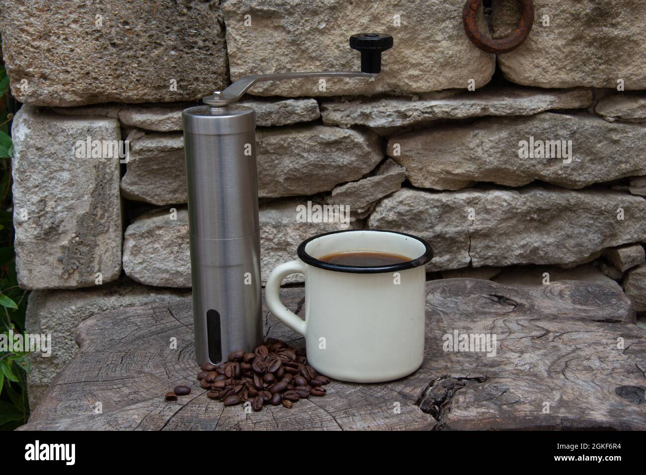 lightweight coffee grinder for camping and the outdoor life with enamal coffee cup and beans . Stock Photo
