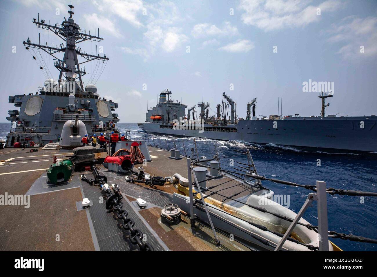 SOUTH CHINA SEA (April 06, 2021) - Arleigh Burke-class guided-missile destroyer USS Barry (DDG 52) conducts a replenishment-at-sea with Lewis and Clark class dry cargo ship USNS Pecos. Barry is assigned to Task Force 71/Destroyer Squadron FIFTEEN (DESRON 15), the Navy’s largest forward deployed DESRON and the U.S. 7th Fleet’s principal surface force. Stock Photo