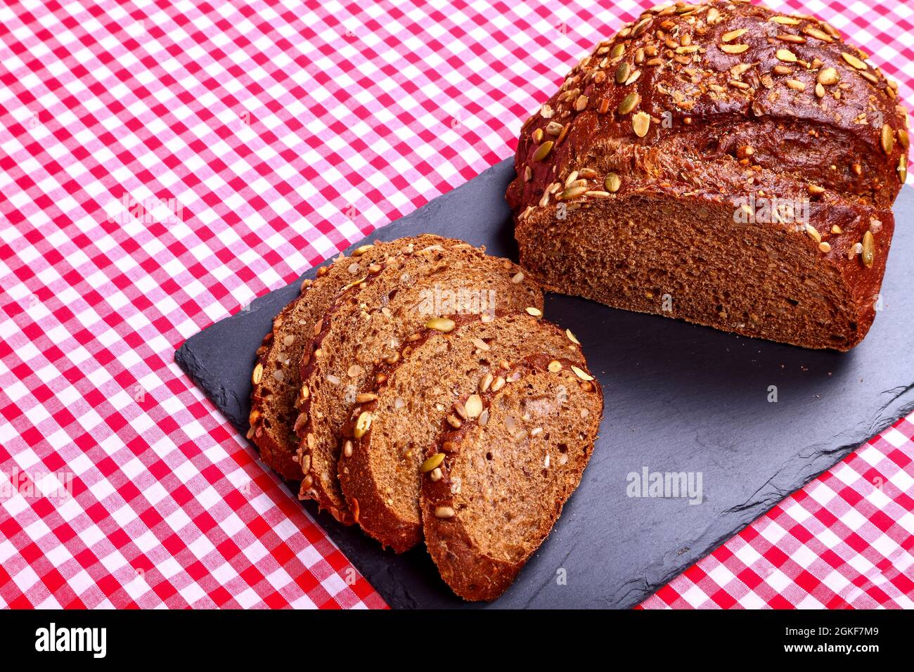 Freshly baked Pumpernickel Boule artisan bread with bread slices cut and laid on a slate serving platter Stock Photo