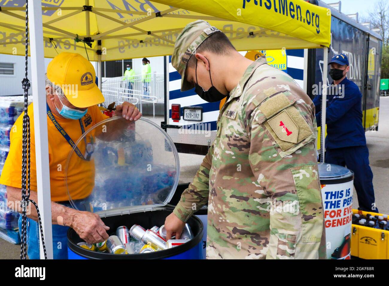 James Crabtree, left, a volunteer with the Texas Baptist Ministry, offers a drink to U.S. Army Spc. Kevin Kalnai, a combat medic assigned to 2nd Battalion 70th Armor Regiment, 2nd Armored Brigade Combat Team, 1st Infantry Division, at the Fair Park Community Vaccination Center (CVC) in Dallas, April 7, 2021. Crabtree, a former U.S. Air Force Airman, has been a disaster relief volunteer since 2017. U.S. Northern Command, through U.S. Army North, remains committed to providing continued, flexible Department of Defense support to the Federal Emergency Management Agency as part of the whole-of-gov Stock Photo