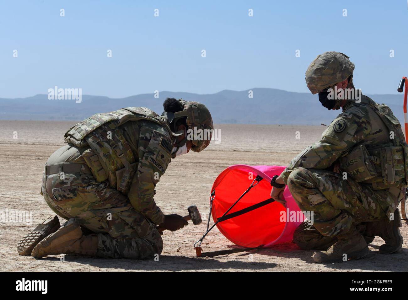 .S. Army Spc. Alexus Dickerson (left) and Sgt. Ethan Castle (right), air traffic control (ATC) operators with the 2nd Battalion, 111th Aviation Regiment in support of Combined Joint Task Force-Horn of Africa (CJTF-HOA), set up a VS-17 panel marker at Grand Bara, Djibouti, April 7, 2021. The team set up various VS-17 panel markers in order to mark a landing zone for a C-130 Hercules aircraft during a low-level landing exercise. Stock Photo